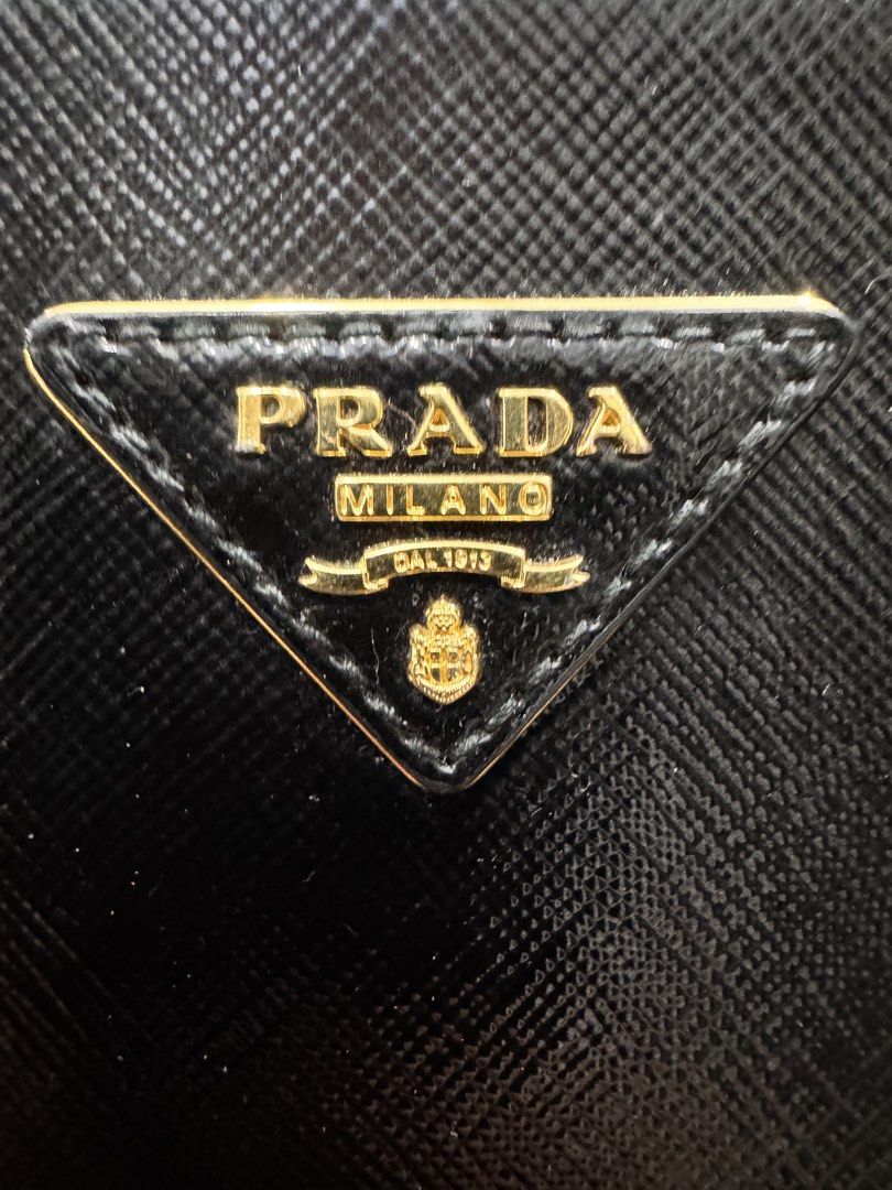 Prada Saffiano Leather Black Dome Handbag (Category: Luxury Bags & Wallets) located in Quezon City. Submitted by derill_shop (Listing ID 1451022954, Image 2). Description: - Classic black Prada dome handbag - Made from durable Saffiano leather - Elegant gold hardware details - Includes a detachable shoulder strap for versatile carrying - Comes with a signature Prada key charm - Spacious interior to hold your essentials - Ideal for both work and e