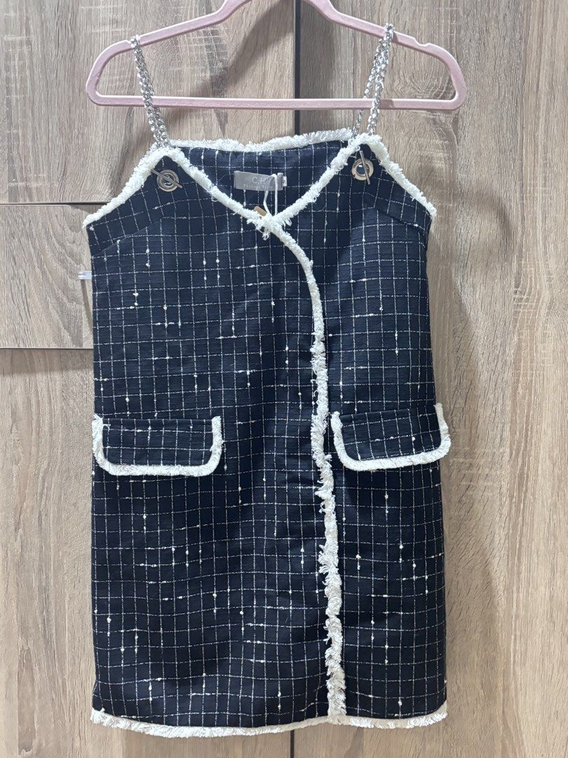 Black Grid Tweed Dress with Chain Straps (Category: Dresses) located in Manila. Submitted by laijane (Listing ID 1451157547, Image 1). Description: - Black tweed dress with a classic grid pattern. - Elegant white frayed trim on neckline and pockets. - Stylish silver chain straps. - Decorative button details on the shoulders. - Two functional front pockets. - Estimated size: Small to Medium. - Versatile for both casual outings and evening events..