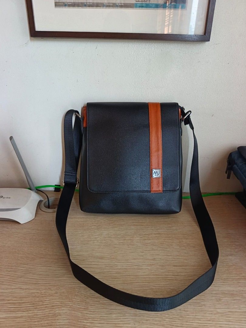 Black Leather Messenger Bag with Orange Accent (Category: Luxury Bags & Wallets) located in Taguig. Submitted by jaybrandedstore (Listing ID 1451200092, Image 1). Description: - Mcjim Genuine leather black messenger bag -Brand new and never been used - Eye-catching orange stripe detail - Interior lining with a repeating pattern - Adjustable strap for comfortable carrying - Spacious main compartment for essentials - Convenient zipped pocket on the