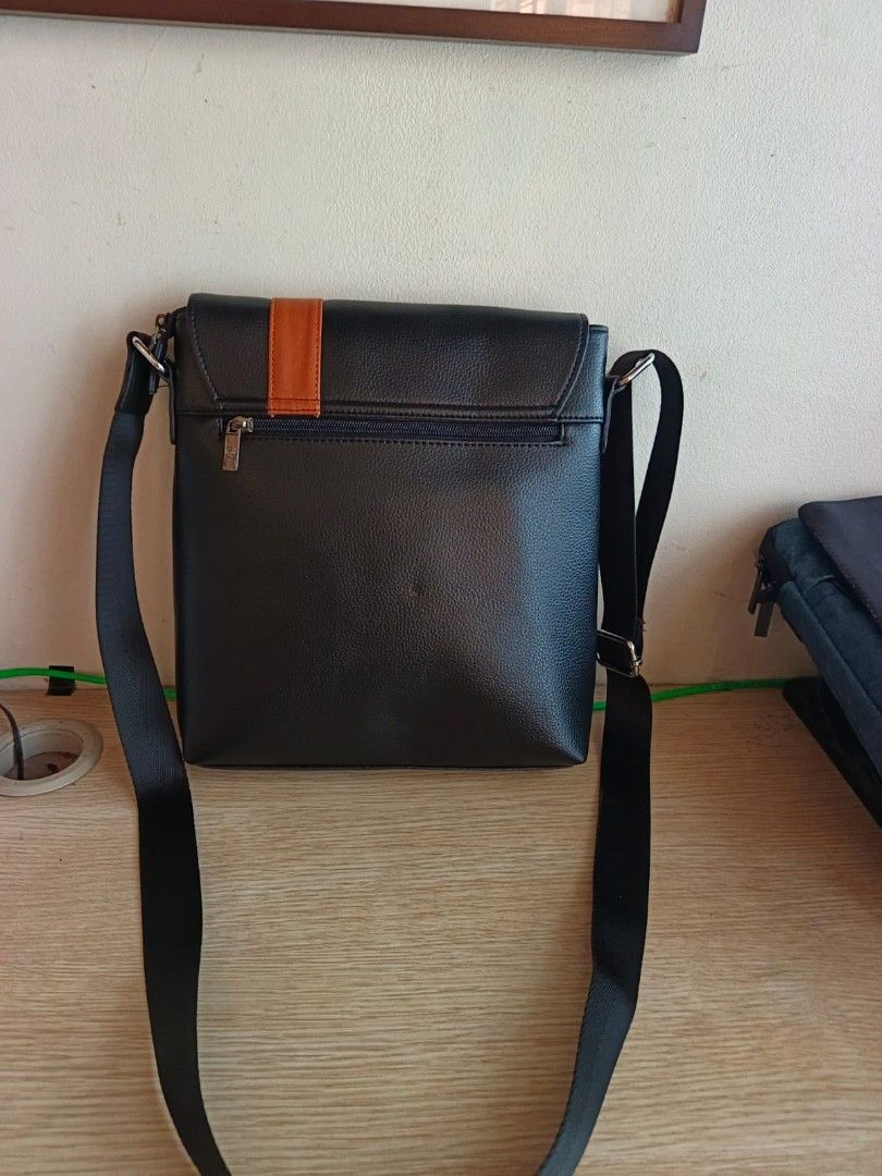 Black Leather Messenger Bag with Orange Accent (Category: Luxury Bags & Wallets) located in Taguig. Submitted by jaybrandedstore (Listing ID 1451200092, Image 2). Description: - Mcjim Genuine leather black messenger bag -Brand new and never been used - Eye-catching orange stripe detail - Interior lining with a repeating pattern - Adjustable strap for comfortable carrying - Spacious main compartment for essentials - Convenient zipped pocket on the