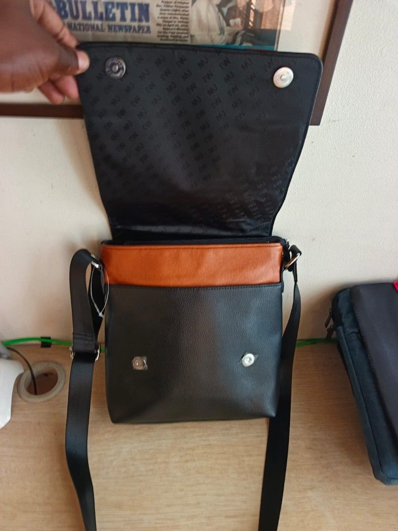 Black Leather Messenger Bag with Orange Accent (Category: Luxury Bags & Wallets) located in Taguig. Submitted by jaybrandedstore (Listing ID 1451200092, Image 3). Description: - Mcjim Genuine leather black messenger bag -Brand new and never been used - Eye-catching orange stripe detail - Interior lining with a repeating pattern - Adjustable strap for comfortable carrying - Spacious main compartment for essentials - Convenient zipped pocket on the