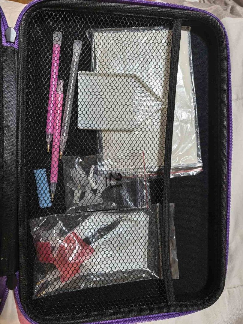 Diamond Painting Storage Case with Accessories (Category: Craft Supplies & Tools) located in Quezon City. Submitted by purple_chick (Listing ID 1451180217, Image 3). Description: - Black organizer case with purple trim and handle - Features many small clear containers for beads or gems - Comes with various tools like pens, a small blue eraser, and other accessories in sealed bags - Ideal for organizing diamond painting supplies.