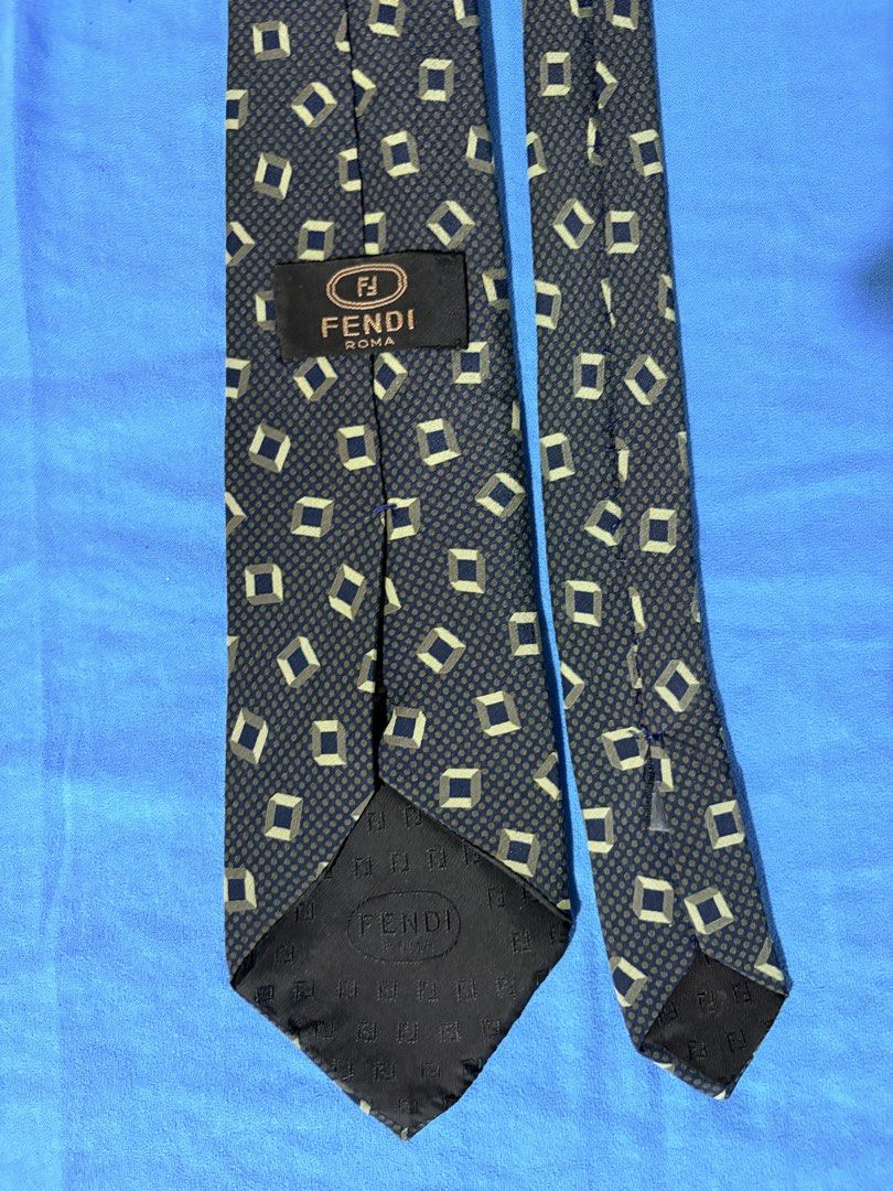 Fendi Roma Silk Tie (Category: Ties) located in Manila. Submitted by truedeclutter (Listing ID 1451202710, Image 3). Description: - Classic Fendi tie - Geometric pattern: Dark navy base with beige and green diamond shapes - Material: 100% Silk - Perfect for formal occasions or adding luxury to any outfit - Length: Approximately 57 inches - Widest part of blade: Approximately 3.5 inches.