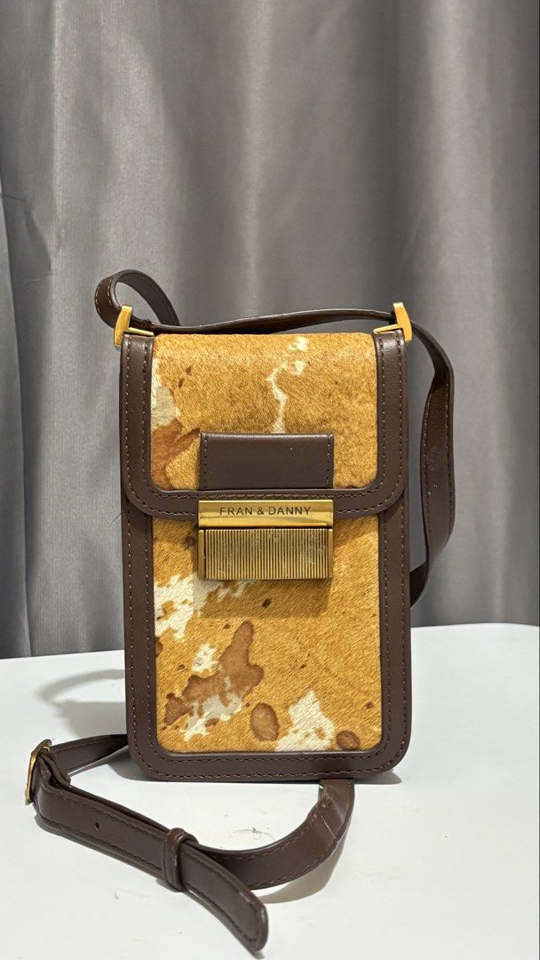 Fran & Danny Cow Print Crossbody Bag (Category: Cross-body Bags) located in Bato. Submitted by kikiwasabiii67 (Listing ID 1451258253, Image 1). Description: - Adorable cow print crossbody bag - Stylish brown leather trim - Secure interior zipper closure - Adjustable strap for comfort - Ideal for carrying your daily essentials.