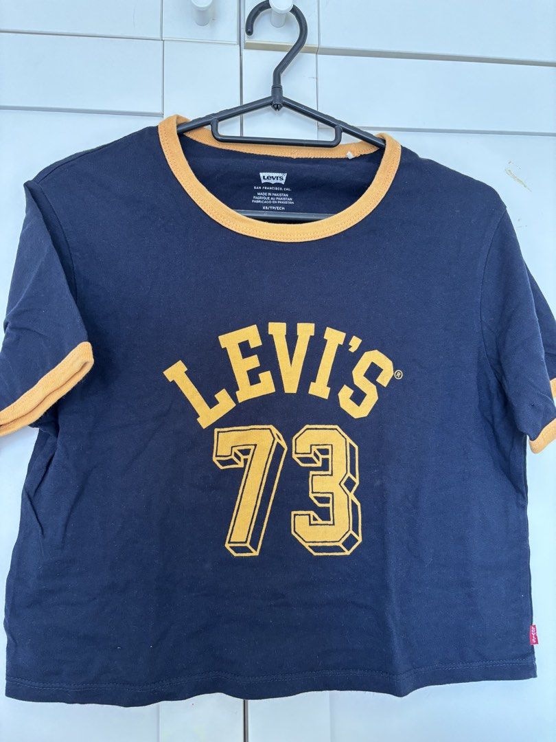 Levis jersey navy and yellow （分類：T-shirt）位於 Hong Kong。 由 user529021076 提交（商品編號 1451214809，圖片 1）。簡介： Hey there! Up for grabs is this super cool Levis jersey in a classic navy and yellow combo. It's got that retro vibe with the 'Levi's 73' graphic on the front, perfect for adding a touch of vintage style to your outfit. The ringer tee design with the yellow trim on the collar and sleeves gives it a sporty feel. This one's a size XS, so it's great f