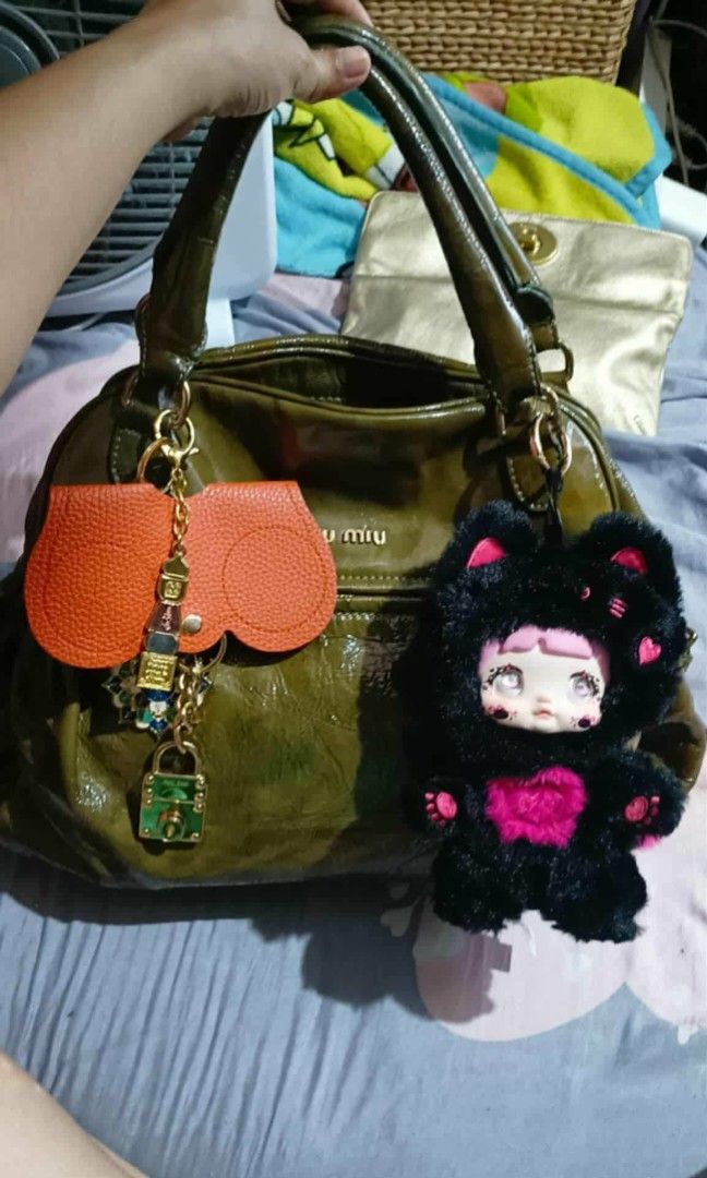 Miu Miu Patent Leather Handbag (Category: Luxury Bags & Wallets) located in Quezon City. Submitted by cloudymay (Listing ID 1450872247, Image 1). Description: - Glossy olive green Miu Miu handbag - Prominent Miu Miu logo - Secure magnetic closure - Unique lock detail with chain - Crinkled patent leather finish - Sturdy handles attached with buckles - Ideal for stylish everyday use * Accesories not included. Its just a suggestion as to how I style
