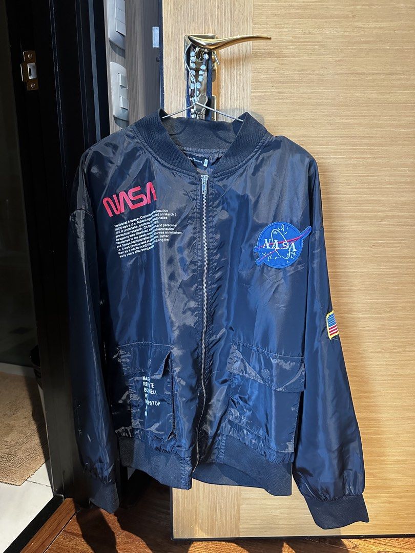 NASA Bomber Jacket (Category: Coats, Jackets and Outerwear) located in Manila. Submitted by xandercoronel (Listing ID 1451200637, Image 1). Description: - Stylish NASA bomber jacket - Features iconic NASA logo on chest and sleeve - Includes text details on the front - American flag patch on the sleeve - Two front pockets with secure button closure - Comfortable ribbed cuffs and hem - Ideal for space enthusiasts and collectors.