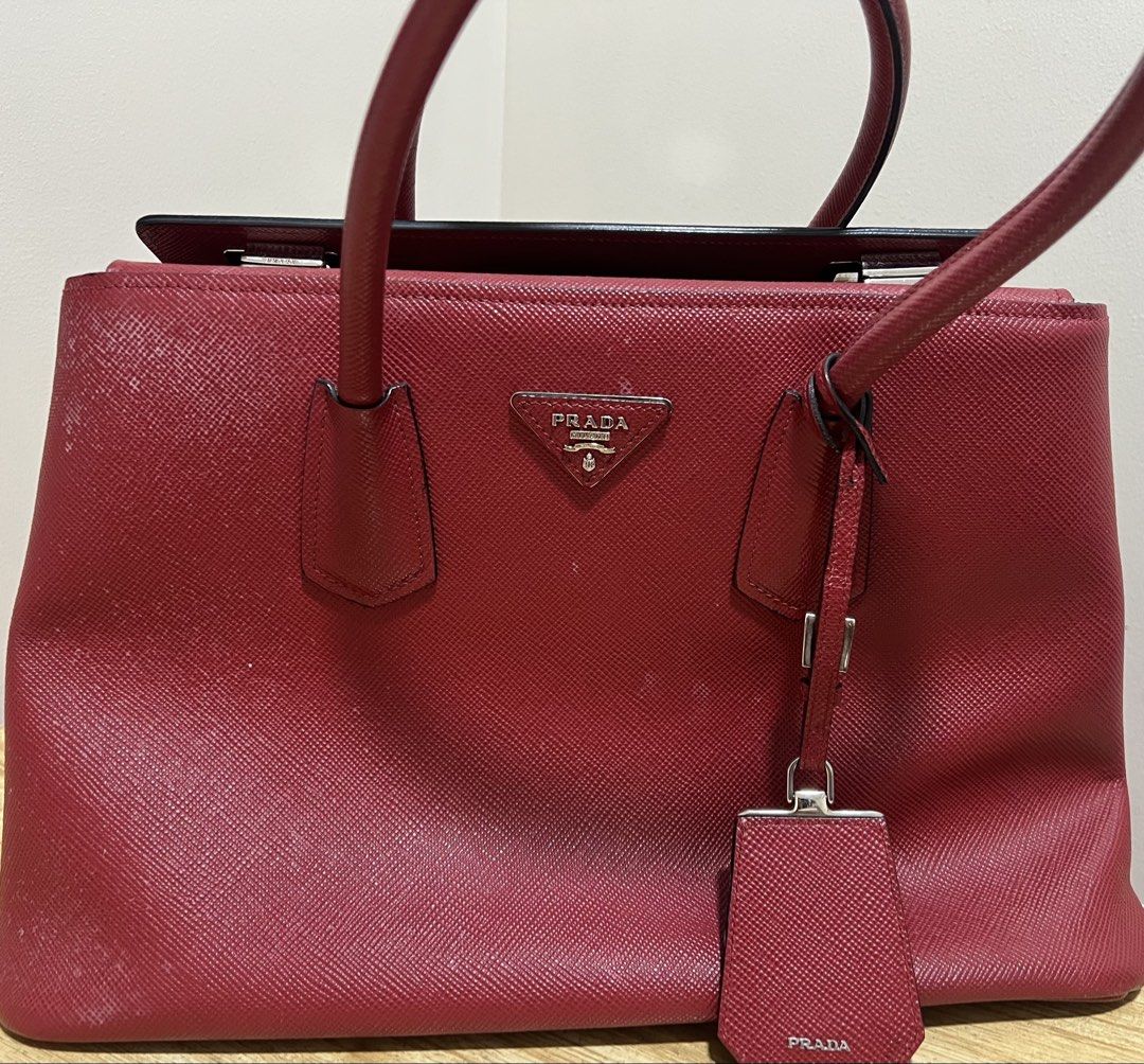 Prada Saffiano Leather Top Handle Bag (Category: Luxury Bags & Wallets) located in Makati City. Submitted by classyandchic (Listing ID 1451293617, Image 1). Description: - Authentic Red Prada Saffiano Leather Bag - Features top handles and a detachable shoulder strap - silver hardware - Comes with entrupy authentication - with stain (can be removed) .