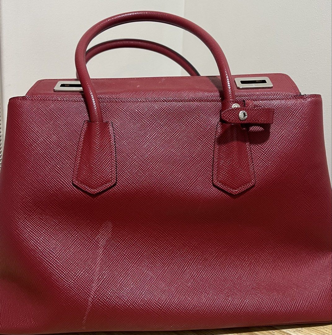 Prada Saffiano Leather Top Handle Bag (Category: Luxury Bags & Wallets) located in Makati City. Submitted by classyandchic (Listing ID 1451293617, Image 2). Description: - Authentic Red Prada Saffiano Leather Bag - Features top handles and a detachable shoulder strap - silver hardware - Comes with entrupy authentication - with stain (can be removed) .