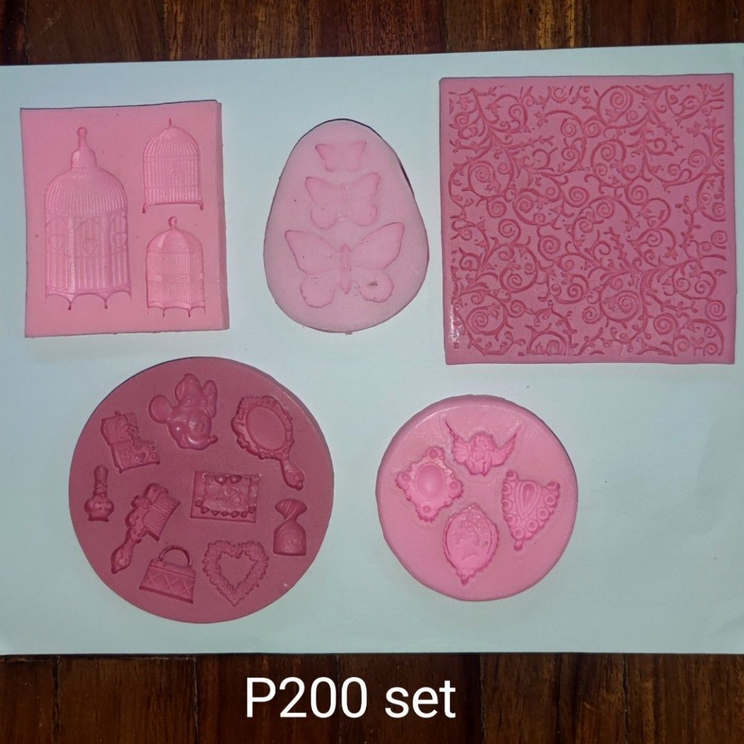 Silicone Molds for Baking or Clay (Category: Bakeware) located in Muntinlupa City. Submitted by angeline_cga (Listing ID 1451152618, Image 1). Description: - Set of 5 pink silicone molds - Perfect for baking, soap making, or resin crafts - Designs include birdcages, butterflies, ornate patterns, mirrors, and handbags - Great for adding decorative details to your creations - Price: P200 for the entire set.