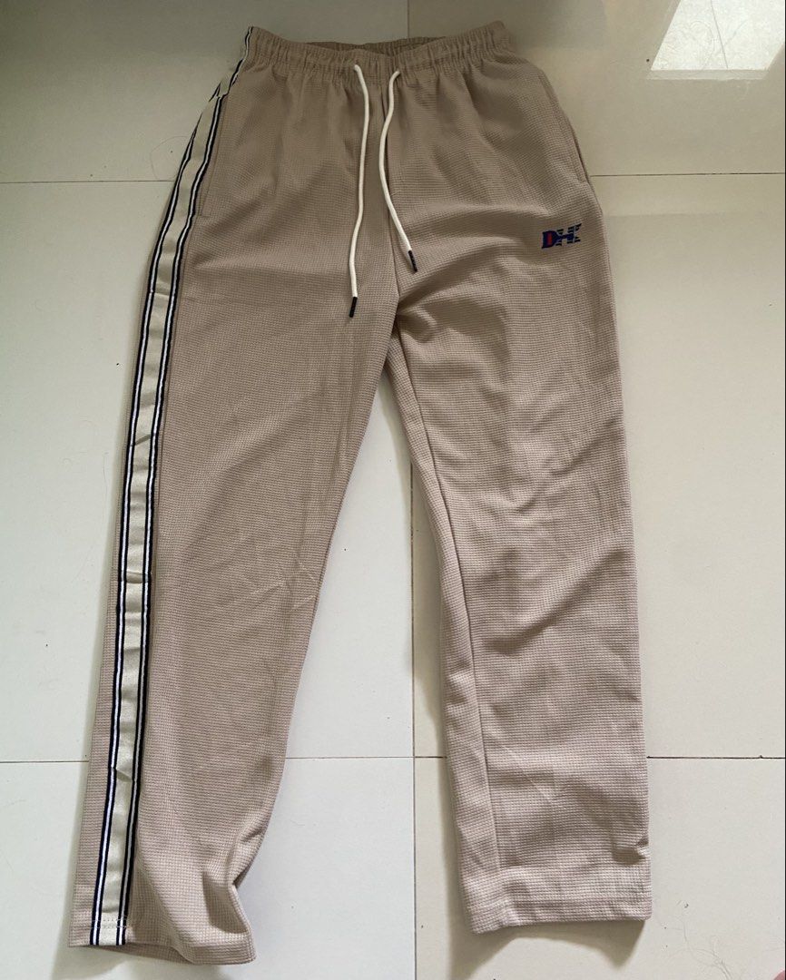 ⭐️Tan Track Pants with Side Stripe (Category: Other Bottoms) located in Bangui. Submitted by loricam (Listing ID 1451246097, Image 1). Description: - Tan colored track pants - Waffle knit texture for comfort - White drawstring at the waist - Side stripe detail (white, black, blue) - Small embroidered logo on left thigh - Perfect for casual wear Free Shipping for 1k plus worth of orders .