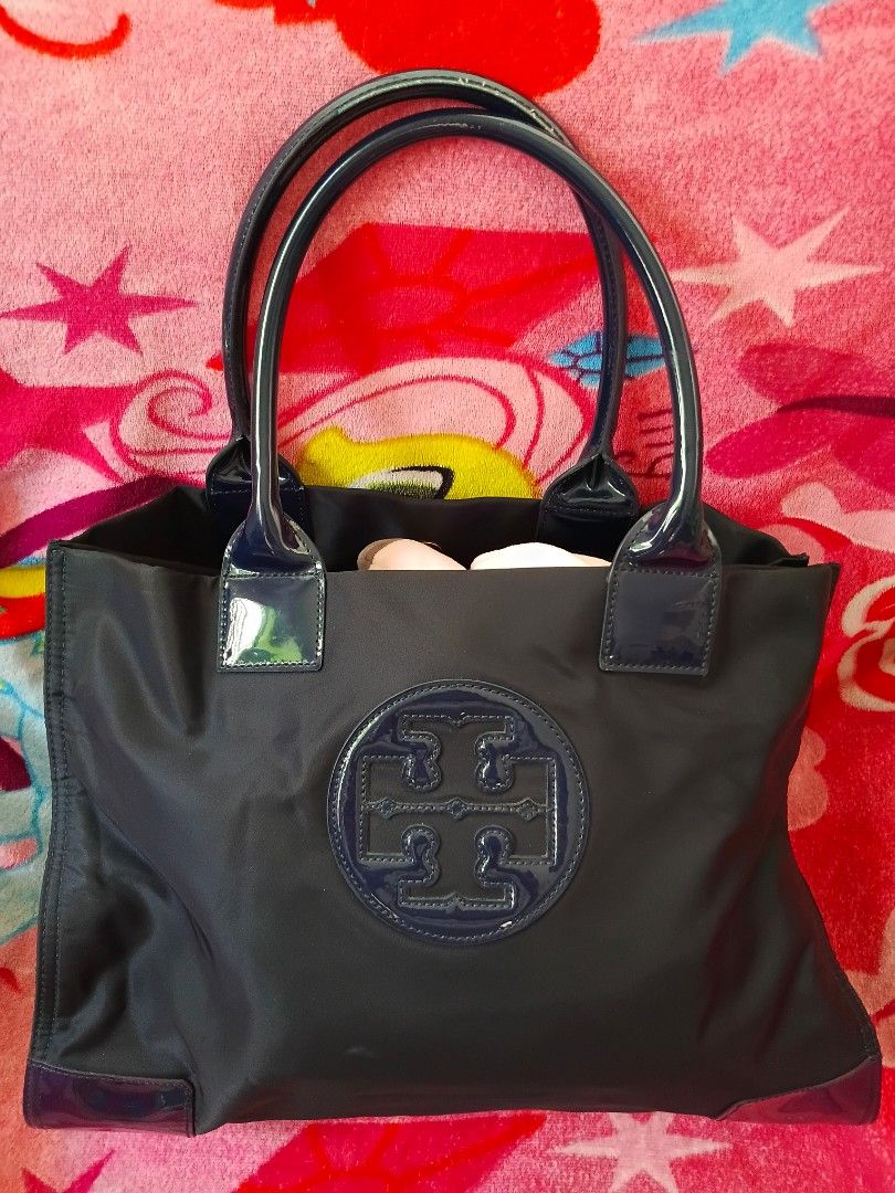 Tory Burch Nylon Tote Bag (Category: Luxury Bags & Wallets) located in Binangonan. Submitted by chingtp (Listing ID 1451186877, Image 1). Description: - Authentic Tory Burch tote bag in classic navy blue - Durable and lightweight nylon material with elegant patent leather trim. - Signature Tory Burch logo prominently displayed on the front. - Multiple interior pockets for excellent organization. - Sturdy and comfortable handles for easy carrying.
