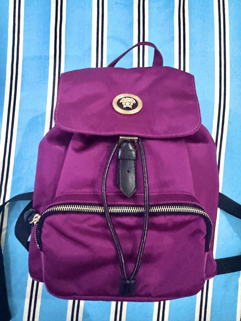 Versace Medusa Purple Nylon Backpack (Category: Backpacks) located in Dagupan City. Submitted by pardonmyfrench2025 (Listing ID 1451258391, Image 1). Description: - Purple nylon backpack - Iconic gold Medusa head emblem - Secure drawstring closure with magnetic snap flap - Convenient front zip pocket - Adjustable shoulder straps featuring Versace's signature Greek key pattern - Ideal for everyday wear and stylish outings.