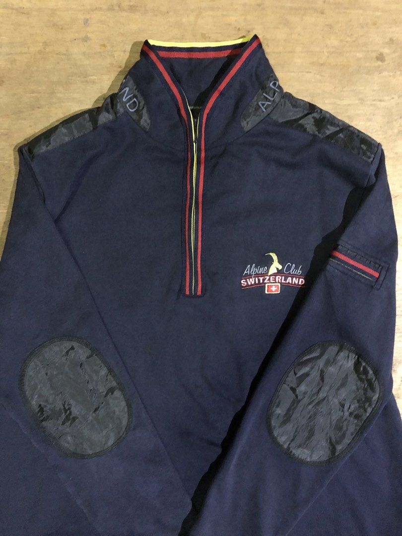 ALPINE CLUB SWITZERLAND SWEATSHIRT (Category: Coats, Jackets and Outerwear) located in Davao. Submitted by blufinds (Listing ID 1451454150, Image 3). Description: This is a navy blue quarter-zip sweatshirt from Alpine Club Switzerland featuring a distinct red, yellow, and blue striped collar and placket detail, as well as an embroidered logo patch on the chest..