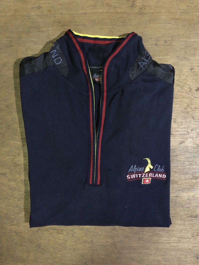 ALPINE CLUB SWITZERLAND SWEATSHIRT (Category: Coats, Jackets and Outerwear) located in Davao. Submitted by blufinds (Listing ID 1451454150, Image 2). Description: This is a navy blue quarter-zip sweatshirt from Alpine Club Switzerland featuring a distinct red, yellow, and blue striped collar and placket detail, as well as an embroidered logo patch on the chest..