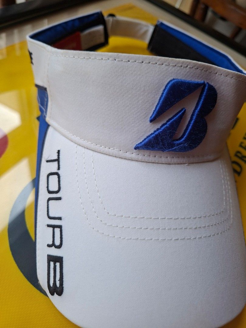Bridgestone Golf Tour B White Blue Visor (Category: Golf) located in Makati City. Submitted by elmer.fudd (Listing ID 1451345262, Image 2). Description: - Bridgestone Golf Tour B Visor - Color: White with blue accents - Features Bridgestone Golf logo - Adjustable strap for a comfortable fit - Perfect for sunny days on the golf course - Note: Shows some signs of wear on the inner band.