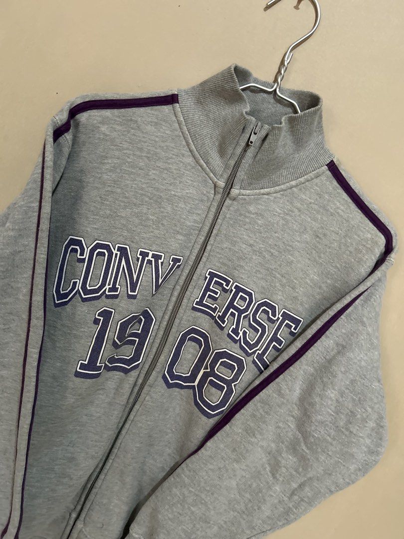 Converse 1908 Grey Track Jacket (Category: Coats, Jackets and Outerwear) located in Baliuag. Submitted by declutterbynadz (Listing ID 1451390148, Image 2). Description: - Grey Converse track jacket - Purple stripe details - 'Converse 1908' graphic on front - Full zip closure - Stand-up collar - Size: Medium (M) - Ideal for casual wear and layering - Comfortable and stylish.