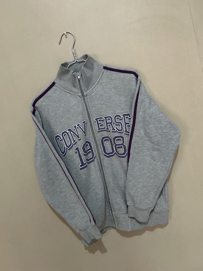 Converse 1908 Grey Track Jacket (Category: Coats, Jackets and Outerwear) located in Baliuag. Submitted by declutterbynadz (Listing ID 1451390148, Image 3). Description: - Grey Converse track jacket - Purple stripe details - 'Converse 1908' graphic on front - Full zip closure - Stand-up collar - Size: Medium (M) - Ideal for casual wear and layering - Comfortable and stylish.