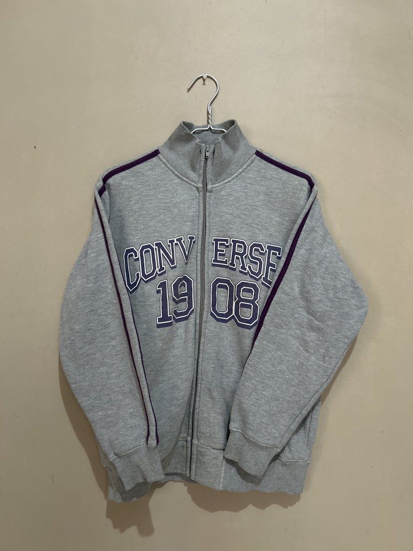 Converse 1908 Grey Track Jacket (Category: Coats, Jackets and Outerwear) located in Baliuag. Submitted by declutterbynadz (Listing ID 1451390148, Image 1). Description: - Grey Converse track jacket - Purple stripe details - 'Converse 1908' graphic on front - Full zip closure - Stand-up collar - Size: Medium (M) - Ideal for casual wear and layering - Comfortable and stylish.