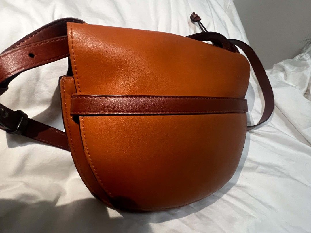 Loewe Gate Small Leather Crossbody Bag Tan (Category: Luxury Bags & Wallets) located in Antipolo. Submitted by happinessprelove (Listing ID 1451456776, Image 3). Description: - Loewe Gate bag - Color: Tan leather - Signature knot detail at the front - Adjustable strap for crossbody or shoulder wear - Gold-tone hardware - Suede lining interior - Made in Spain - Ideal everyday bag.
