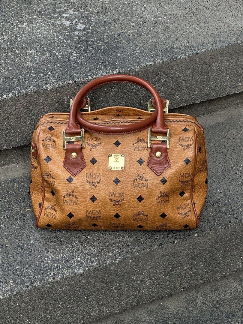 MCM Visetos Monogram Boston Bag / Handbag (Cognac) (Category: Luxury Bags & Wallets) located in Urdaneta. Submitted by redeemedcollective (Listing ID 1451487802, Image 1). Description: Vintage MCM Boston bag in cognac monogram canvas with leather trim and brass hardware. Features a top-zip closure, dual handles, and a spacious interior pocket. Offered in great vintage condition with a natural leather patina. DM for measurements and shipping detai