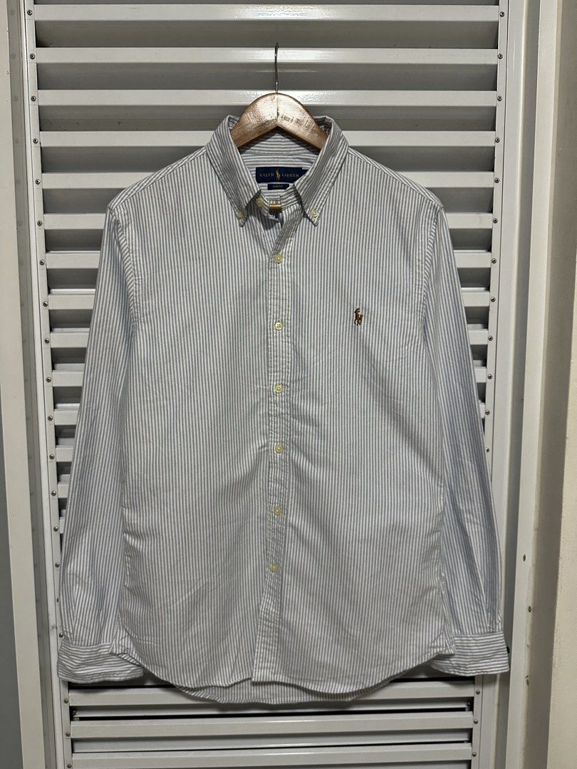 Ralph Lauren Classic Fit Striped Button-Down Shirt (Category: Tshirts & Polo Shirts ) located in Pasig City. Submitted by rl.things (Listing ID 1447067568, Image 2). Description: - Brand: Ralph Lauren - Fit: Classic Fit - Sleeves: Long Sleeve - Pattern: Grey and White Stripe - Features: Embroidered Polo Player Logo on chest, Button-down collar - Style: Versatile for casual or smart-casual occasions.