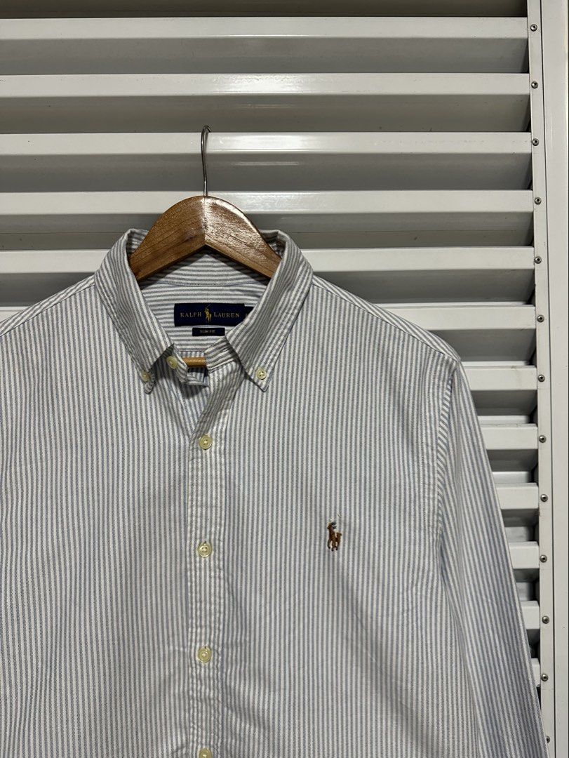 Ralph Lauren Classic Fit Striped Button-Down Shirt (Category: Tshirts & Polo Shirts ) located in Pasig City. Submitted by rl.things (Listing ID 1447067568, Image 1). Description: - Brand: Ralph Lauren - Fit: Classic Fit - Sleeves: Long Sleeve - Pattern: Grey and White Stripe - Features: Embroidered Polo Player Logo on chest, Button-down collar - Style: Versatile for casual or smart-casual occasions.