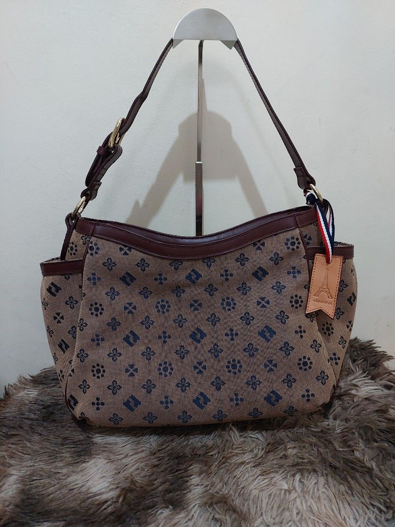 Renoma Monogram Canvas Shoulder Bag (Category: Shoulder Bags) located in Malabon City. Submitted by jullie_bag_shop (Listing ID 1451459779, Image 1). Description: - Brown canvas shoulder bag - Repeating blue monogram pattern - Leather trim and strap - Multiple interior compartments for organization - Gold-tone hardware - Decorative leather tag with Eiffel Tower design - Ideal for everyday use.