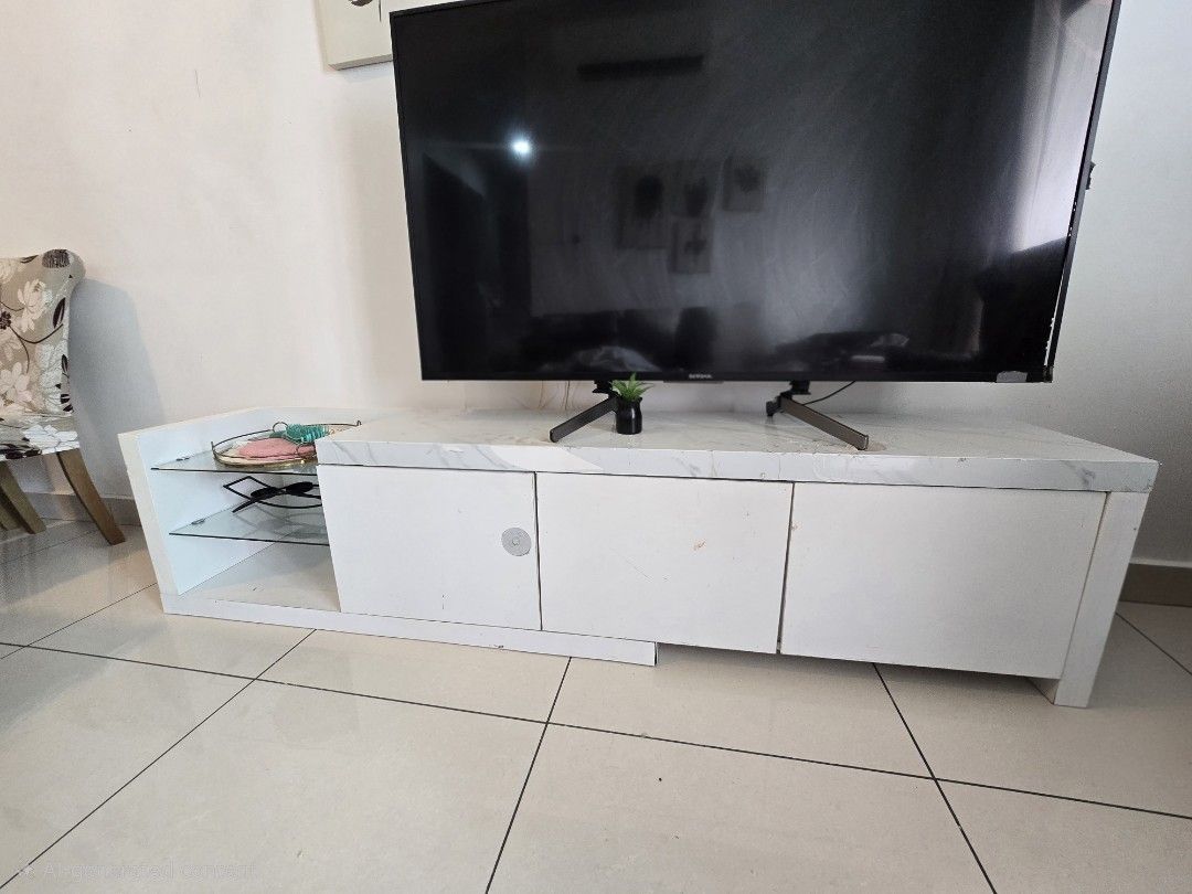 TV Console / Cabinet for Sa (Category: TV Consoles) located in Kuala Lumpur. Submitted by sosokarmi54314 (Listing ID 1451406365, Image 1). Description: Description: Modern white TV cabinet with marble-style top. Features lower storage cabinets and side glass shelves for decor or media players. ​Condition: Used. Has some visible peeling/scratches on the top and edge (shown in pictures) — perfect for a quick DIY fix or wrapping. ​Price: RM 130 (Neg