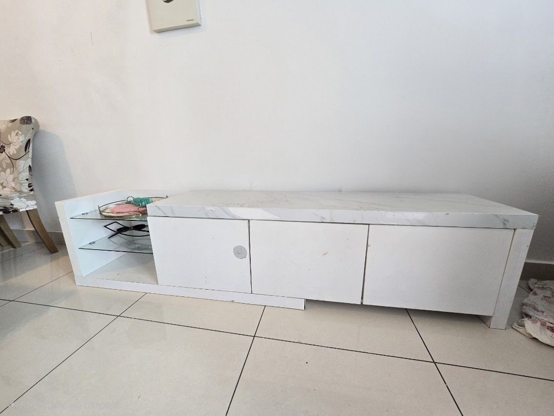 TV Console / Cabinet for Sa (Category: TV Consoles) located in Kuala Lumpur. Submitted by sosokarmi54314 (Listing ID 1451406365, Image 2). Description: Description: Modern white TV cabinet with marble-style top. Features lower storage cabinets and side glass shelves for decor or media players. ​Condition: Used. Has some visible peeling/scratches on the top and edge (shown in pictures) — perfect for a quick DIY fix or wrapping. ​Price: RM 130 (Neg