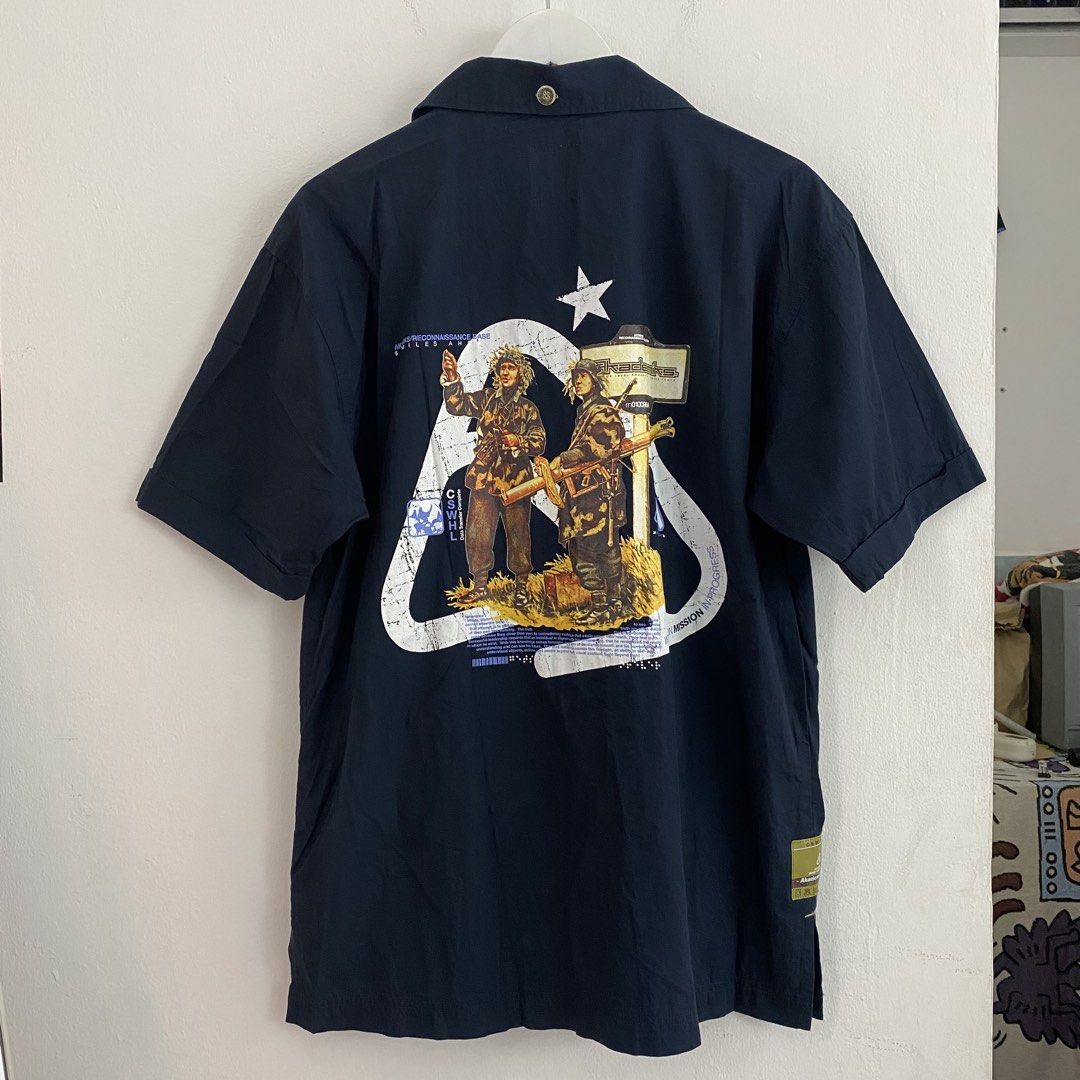 Akademiks Short Sleeve Button Up Shirt Size M (Category: Tshirts & Polo Shirts ) located in Cavite. Submitted by mana__ (Listing ID 1451691519, Image 1). Description: - Navy blue short sleeve button up shirt - Size Medium (M) - Unique graphic print on the back (two figures & '28') - Multiple front pockets with branded details - Ideal for casual wear.