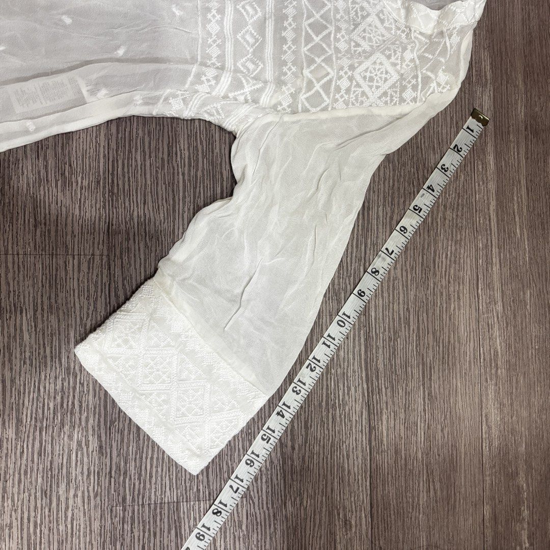 Chico's White Embroidered Sheer Tunic Top (Category: Others Tops) located in Manila. Submitted by angela.gg (Listing ID 1451574343, Image 2). Description: - Brand: Chico's - Type: White Sheer Tunic Top - Size: 1 - Details: Intricate embroidery on neckline, sleeves, and hem - Neckline: V-neck with small button closure - Fabric: Lightweight and airy - Styling: Great for layering or as a beach cover-up.