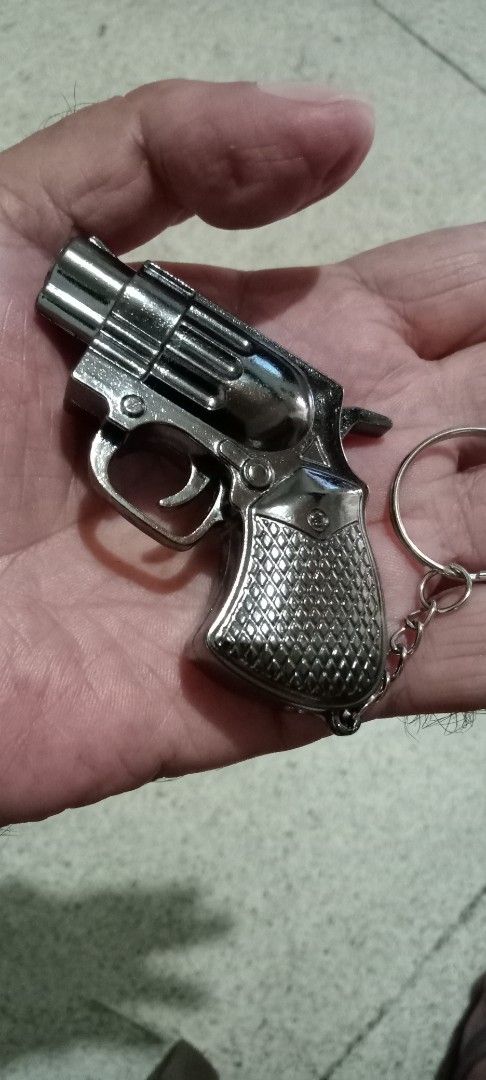 Gun Shaped Lighter Keychain (Category: Craft Supplies & Tools) located in Taytay. Submitted by joselaquino (Listing ID 1451695924, Image 1). Description: - Unique mini revolver shaped lighter - Doubles as a keychain for portability - Lights up with a cool pink flame - Durable metal body, feels solid - Refillable for long-term use - Perfect conversation starter and gift idea.