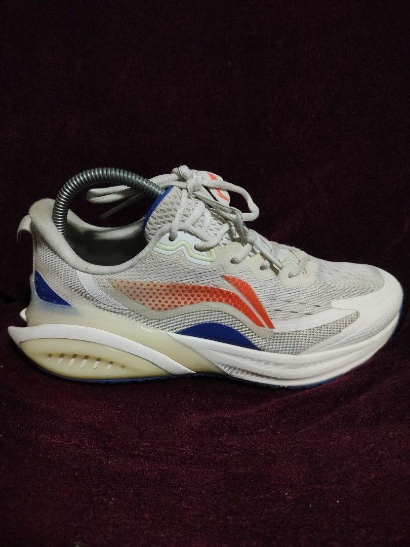 Li-Ning White Running Shoes (Category: Sneakers) located in Malaybalay. Submitted by thrifturessential (Listing ID 1451640995, Image 2). Description: - White Li-Ning running shoes - Breathable mesh upper - Orange and blue accents on the side - Suitable for running or casual wear - Please check photos for detailed condition.