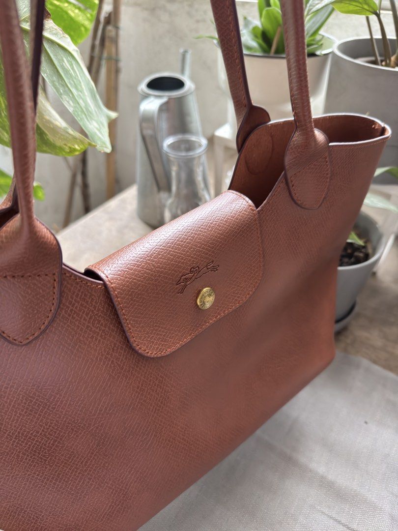 Longchamp Le Pliage Cuir Leather Handbag (Category: Luxury Bags & Wallets) located in Muntinlupa City. Submitted by felma31 (Listing ID 1451608372, Image 3). Description: - Genuine brown leather Longchamp handbag - Iconic embossed logo on the front flap - Two comfortable top handles - Ample interior space for all your essentials - Ideal for everyday use - Meticulously cleaned and well-maintained.