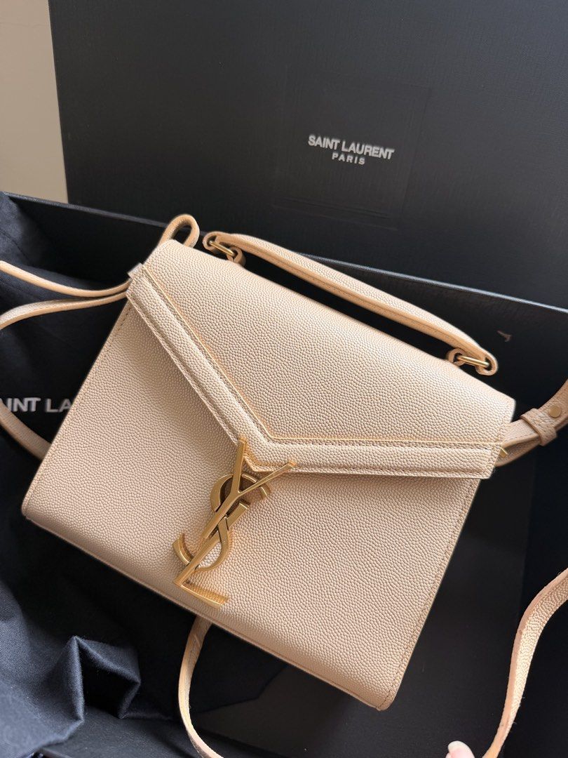 Y S L Beige Leather Handbag (Category: Luxury Bags & Wallets) located in Las Pinas. Submitted by twiceloved24 (Listing ID 1451586231, Image 1). Description: - Iconic gold logo prominently displayed on the front. - Versatile carrying options: top handle and adjustable shoulder strap. - Interior features embossed 'Saint Laurent Paris' detail. - Comes complete with original dust bag and box. - Ideal accessory for both daytime and evening wear..