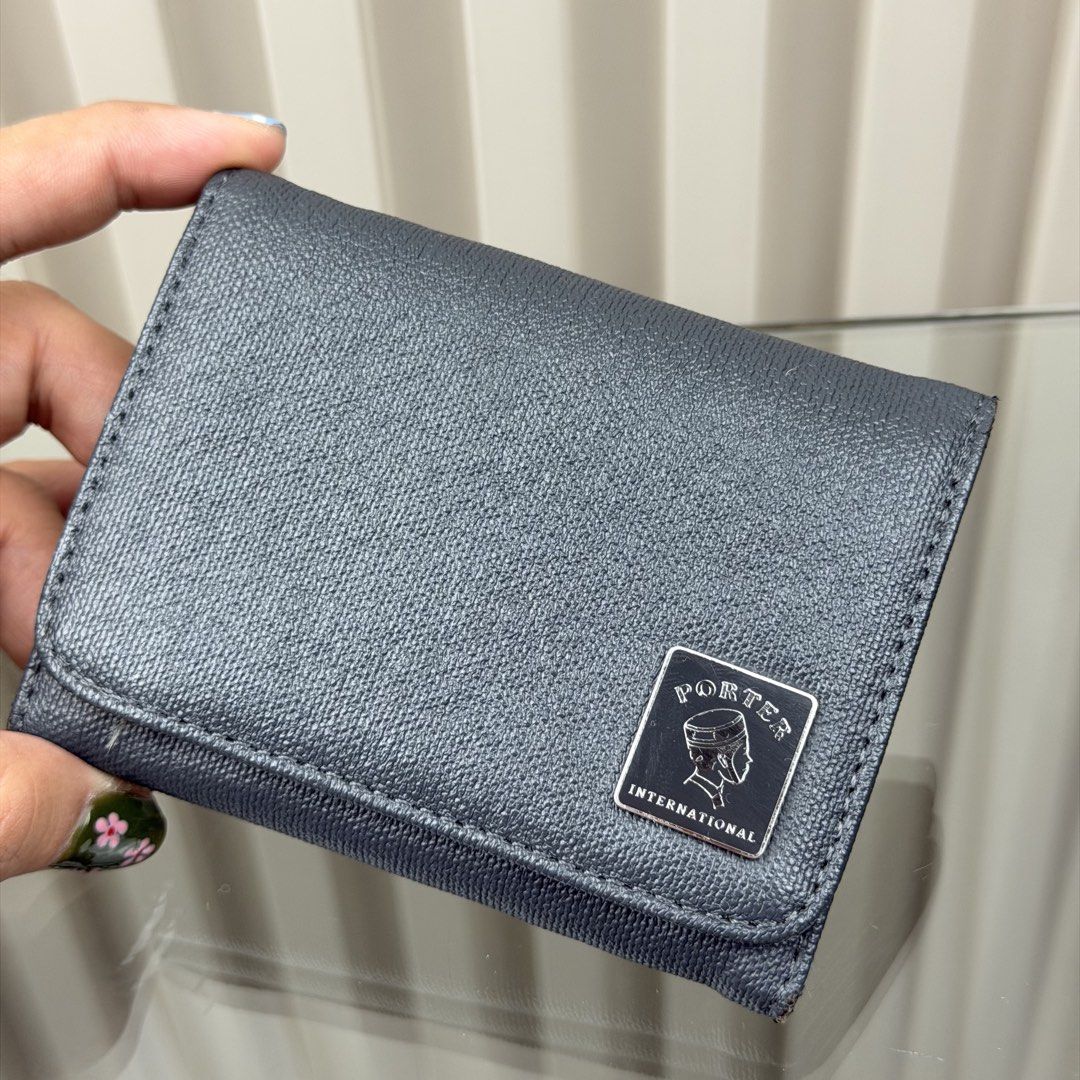 Porter International Tri-fold Wallet (Category: Wallets & Card Holders) located in Pasig City. Submitted by trendapparelph (Listing ID 1451591333, Image 2). Description: - Porter International tri-fold wallet - Dark blue/grey textured material - Features a coin compartment and card slots - Secure snap button closure - Small metal logo plate on the front - Clean interior - Perfect for everyday use.