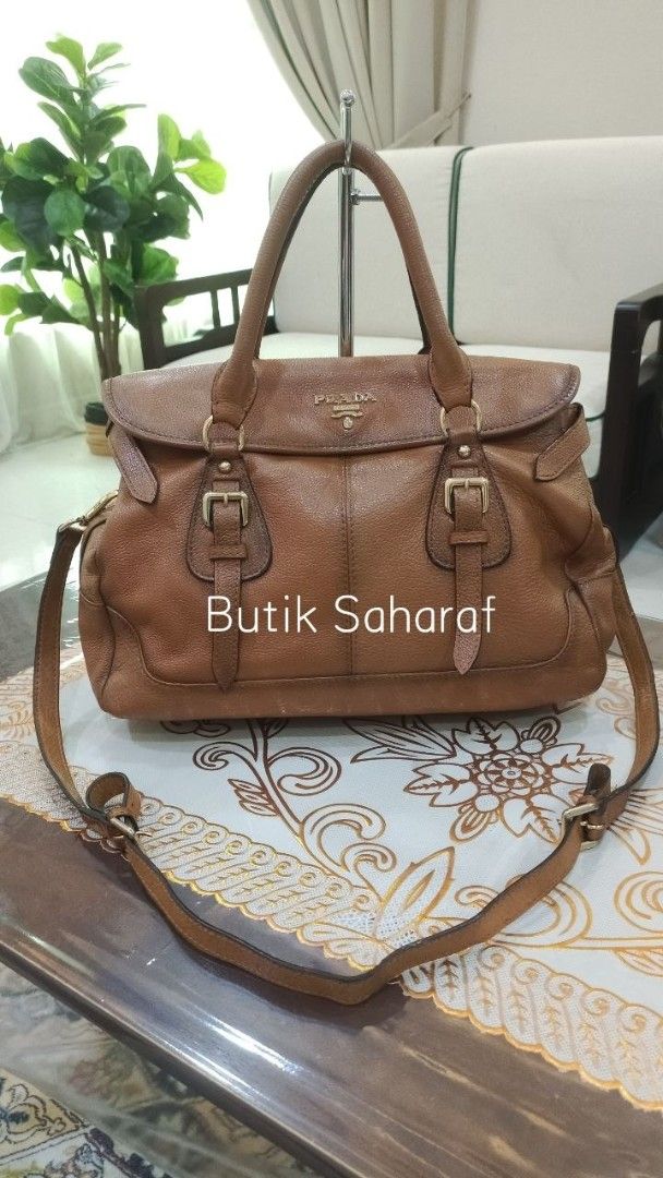 Prada Brown Leather Shoulder Bag (Category: Bags & Wallets) located in Pasir Mas. Submitted by ash_farah (Listing ID 1451555759, Image 1). Description: - Genuine brown leather Prada bag - Versatile with top handles and a detachable shoulder strap - Stylish front buckle detailing - Shows some signs of wear on leather and strap, adding character - Ideal for everyday use, offering both style and practicality - length 36cm .