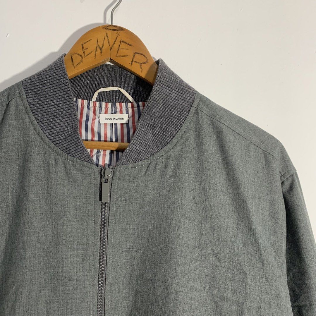 Thom Browne Grey Bomber Jacket Made in Japan (Category: Coats, Jackets and Outerwear) located in Manila. Submitted by gentleflower-74686a (Listing ID 1451672639, Image 2). Description: - Authentic Thom Browne grey bomber jacket - Made in Japan - Signature four-stripe detail on sleeve - Striped lining - Zipper closure - Button pockets - Ribbed collar, cuffs, and hem - Versatile and stylish wardrobe essential.