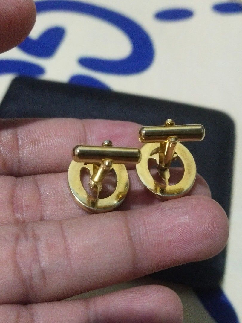 Trussardi Gold Red Enamel Cufflinks (Category: Cuff Links) located in Tuba. Submitted by drickbernard (Listing ID 1451692341, Image 3). Description: - Brand: Trussardi - Material: Gold tone with red enamel - Design: Features the iconic Trussardi greyhound logo - Occasion: Ideal for formal wear or adding flair to any shirt - Includes: One pair of cufflinks.