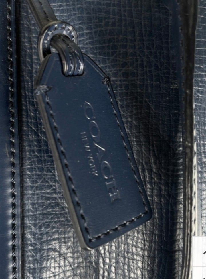 Coach Leather Briefcase Navy Blue (Category: Briefcases) located in Caloocan City. Submitted by noy5o1a (Listing ID 1451843025, Image 3). Description: - Coach navy blue leather briefcase - Textured leather finish for a sophisticated look - Features comfortable top handles - Includes a detachable shoulder strap for versatile carrying options - Comes with original Coach New York hang tag - Ample interior space, ideal for documents, laptop, and esse