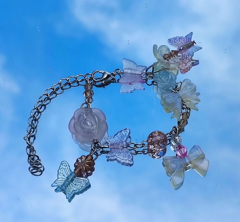 Cute Butterfly and Flower Charm Bracelet (Category: Bracelets) located in Manila. Submitted by chewei12345 (Listing ID 1451881749, Image 1). Description: - Silver chain bracelet with assorted charms - Features translucent blue and purple butterflies - Includes white and pastel roses and bows - Adorned with a pink bead and a textured brown bead - A sweet and whimsical piece to add fun to your style.