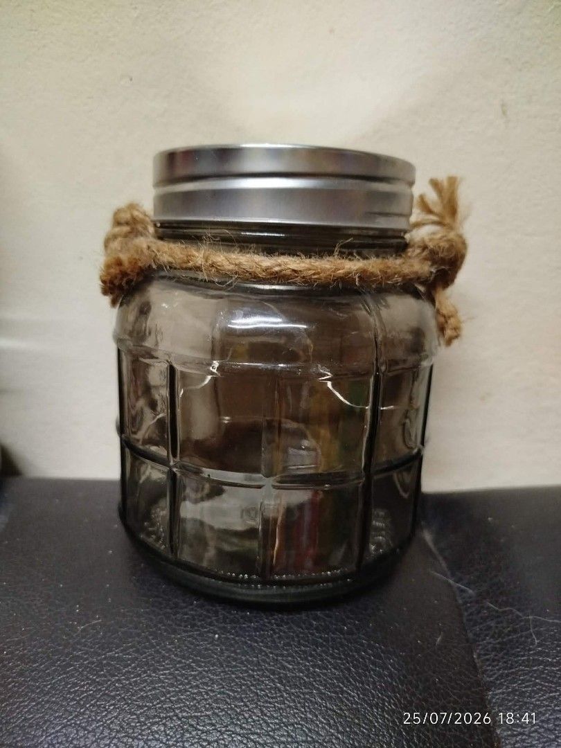 Decorative Glass Jar with Rope Handle (Category: Vases & Decorative Bowls) located in Quezon City. Submitted by chadrison (Listing ID 1451826476, Image 2). Description: - Charming rustic glass jar - Features a textured glass pattern - Comes with a sturdy rope handle - Includes a silver-colored metal lid - Ideal for storage or as a decorative accent - Approximately 10cm in height.