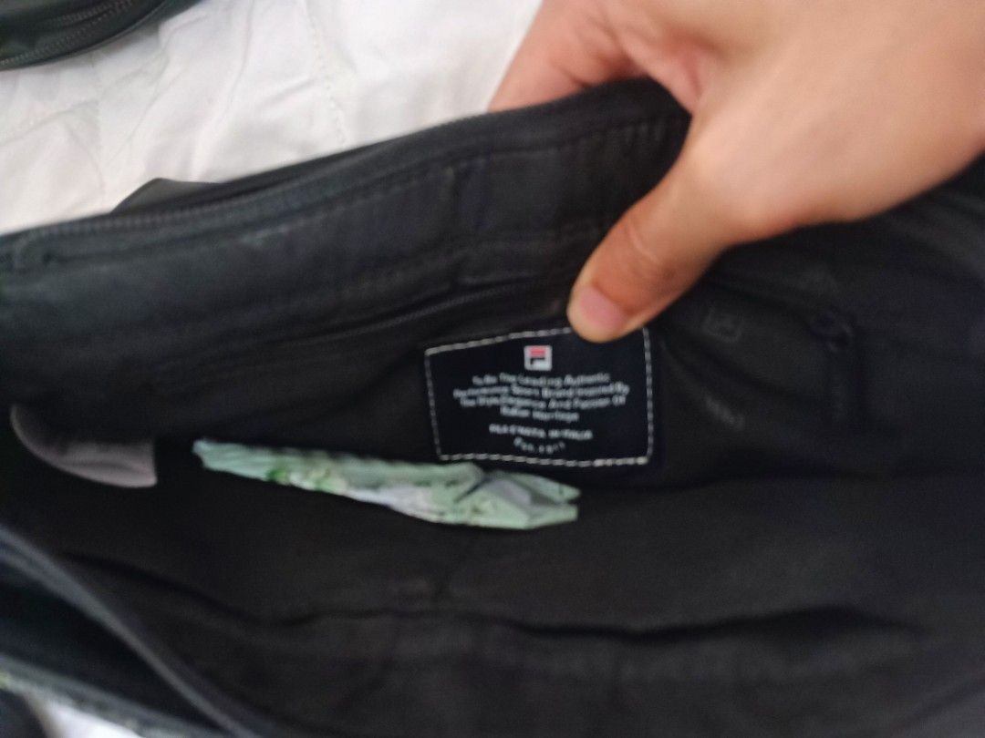 FILA Black Sling Bag (Category: Sling Bags) located in Petaling Jaya. Submitted by junguyenbu83774 (Listing ID 1451779005, Image 3). Description: - Stylish black FILA sling bag - Features a unique patterned front panel - Comes with a separate, attached black pouch - Interior includes a main compartment and a zippered pocket - Adjustable strap for comfortable wear - Ideal for everyday carry.