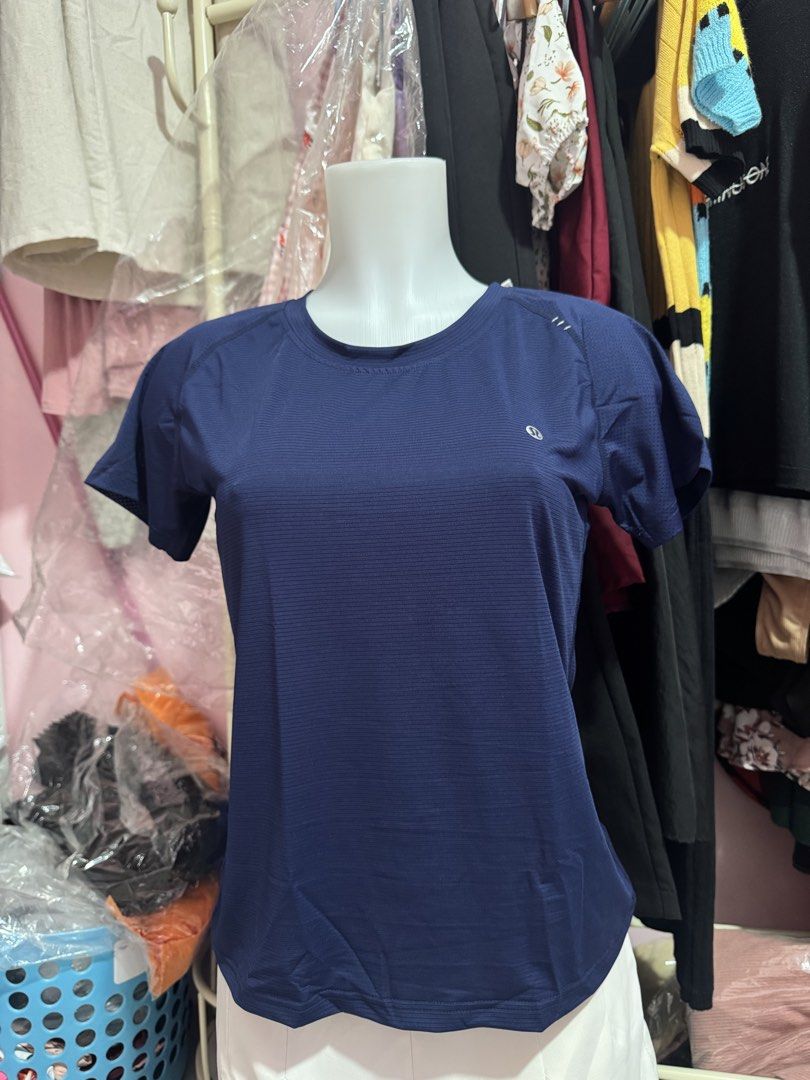 Lululemon Athletic T-shirt - Various Colors (Category: Activewear) located in San Miguel. Submitted by meseszy (Listing ID 1451699347, Image 2). Description: - Brand: Lululemon - Style: Breathable athletic t-shirt - Features: Short sleeves, crew neck, subtle striped texture, Lululemon logo - Back Detail: Lululemon wordmark cut out - Versatile: Ideal for workouts or casual wear - Available Colors: Navy, Lavender, Coral, Light Blue.