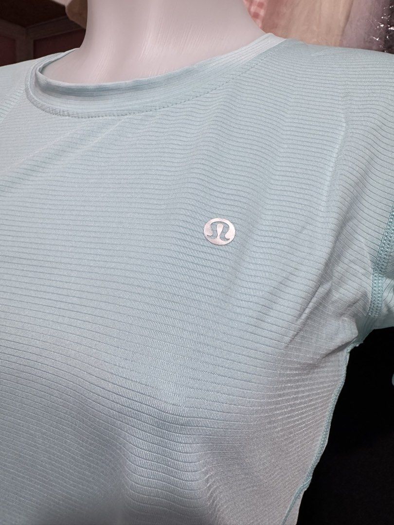 Lululemon Light Blue Athletic T-Shirt (Category: Activewear) located in San Miguel. Submitted by meseszy (Listing ID 1451701723, Image 3). Description: - Light blue Lululemon athletic t-shirt - Short sleeves and crew neck - Subtle textured fabric - Split hem detail on the back - Lululemon logo printed across the upper back - Ideal for workouts or casual wear.