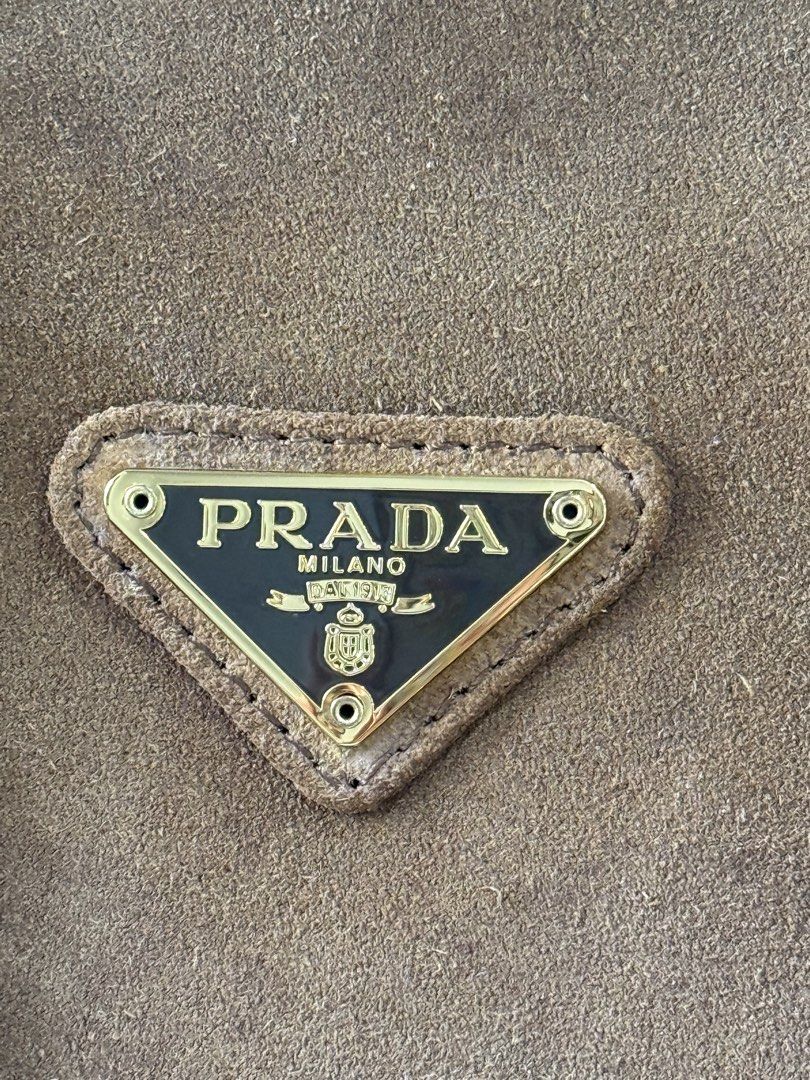 Prada Suede Chain Shoulder Bag (Category: Luxury Bags & Wallets) located in Marikina City. Submitted by _julianpaolo (Listing ID 1451814250, Image 3). Description: - Self-authenticated brown suede Prada shoulder bag from EU thrift shop - Elegant gold chain straps with suede detailing - Secure zipper closure at the top - Iconic Prada triangle logo prominently displayed - Versatile for everyday use or evening events - Offers a flattering shape and 