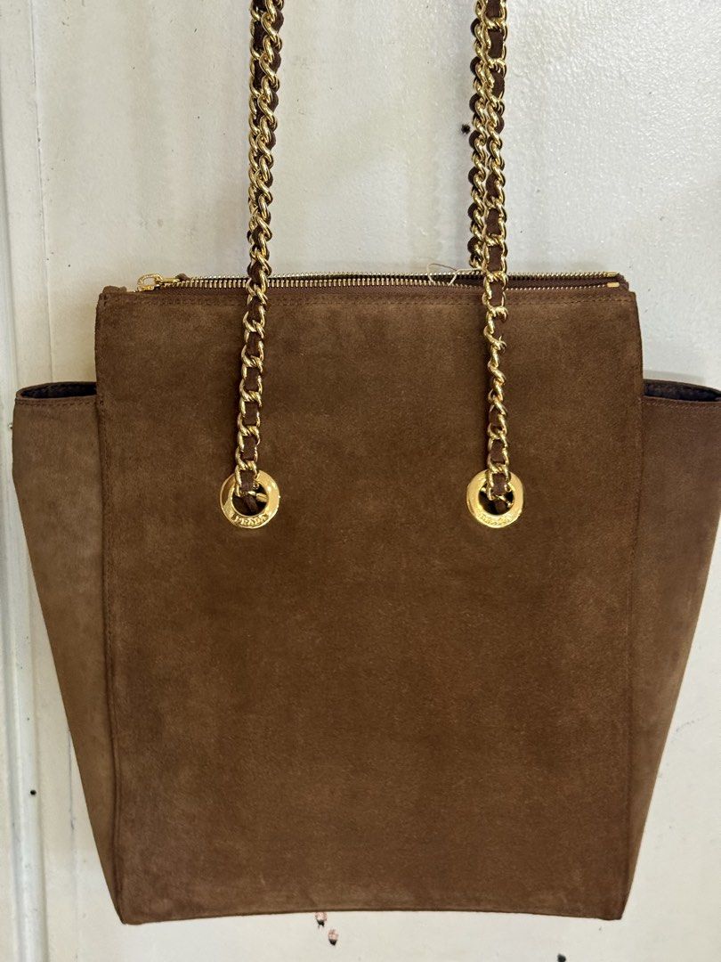 Prada Suede Chain Shoulder Bag (Category: Luxury Bags & Wallets) located in Marikina City. Submitted by _julianpaolo (Listing ID 1451814250, Image 2). Description: - Self-authenticated brown suede Prada shoulder bag from EU thrift shop - Elegant gold chain straps with suede detailing - Secure zipper closure at the top - Iconic Prada triangle logo prominently displayed - Versatile for everyday use or evening events - Offers a flattering shape and 