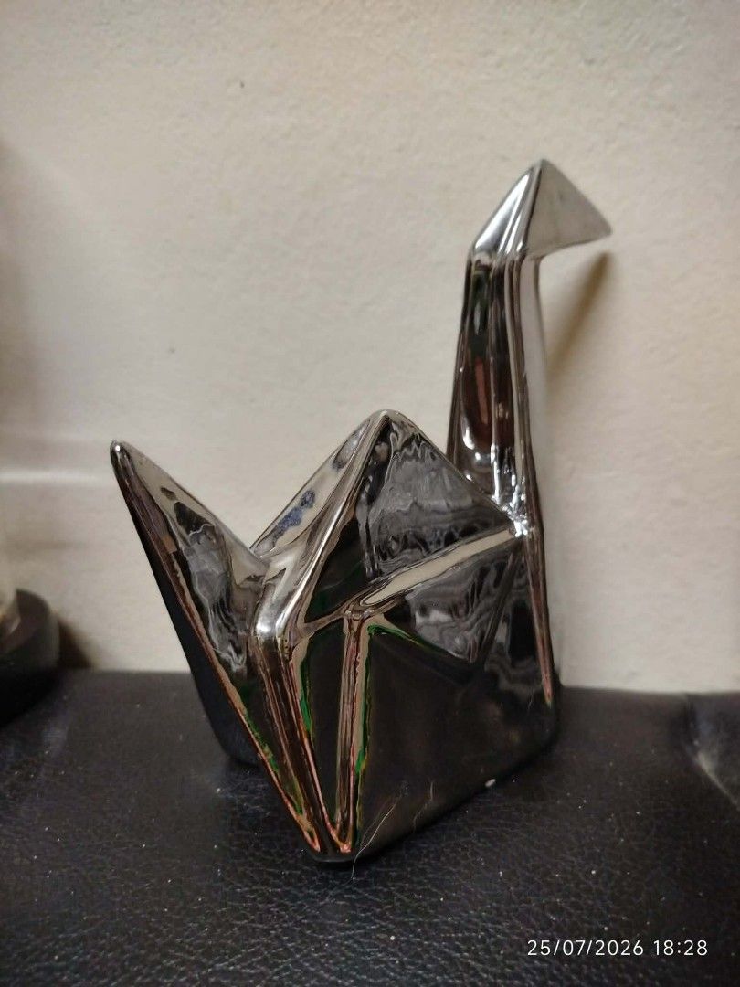 Shiny Silver Origami Crane Decorative Figurine (Category: Other Home Decor) located in Quezon City. Submitted by chadrison (Listing ID 1451825271, Image 2). Description: - Shiny silver decorative piece - Shaped like an origami crane - Polished, reflective surface - Approx. dimensions: 15cm (L) x 10cm (H) - Ideal for shelf or desk display - Adds a modern, artistic touch to your space - Unique home decor item.