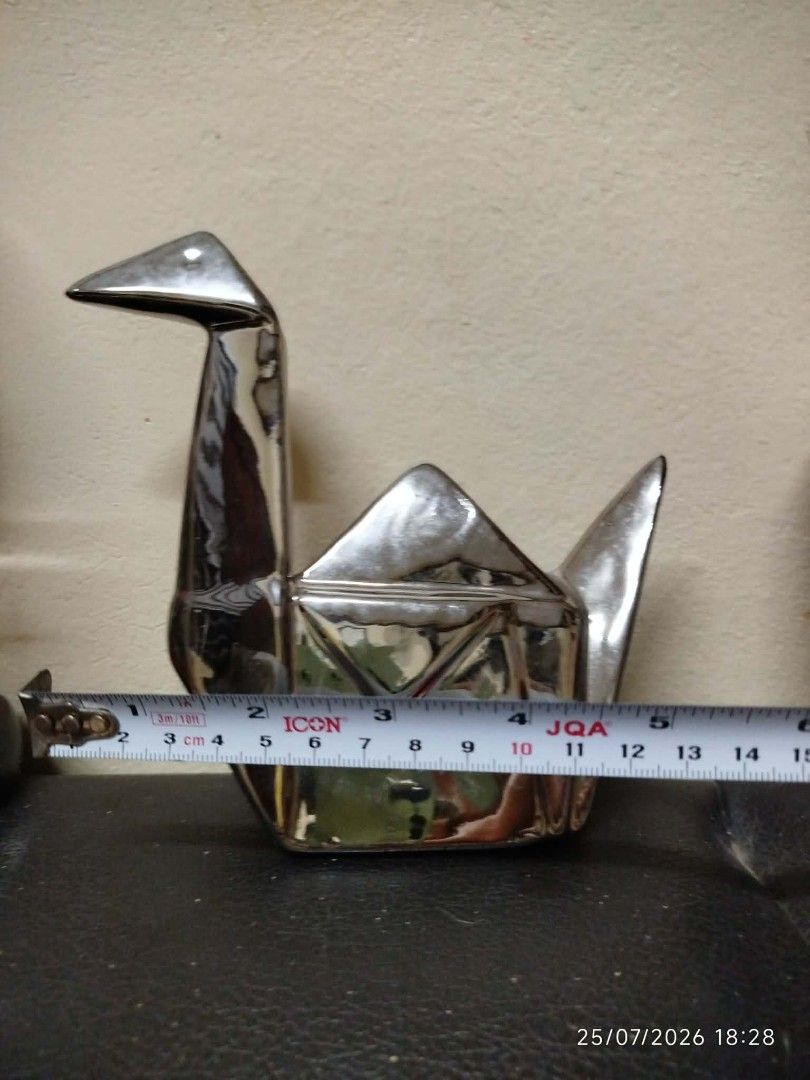 Shiny Silver Origami Crane Decorative Figurine (Category: Other Home Decor) located in Quezon City. Submitted by chadrison (Listing ID 1451825271, Image 3). Description: - Shiny silver decorative piece - Shaped like an origami crane - Polished, reflective surface - Approx. dimensions: 15cm (L) x 10cm (H) - Ideal for shelf or desk display - Adds a modern, artistic touch to your space - Unique home decor item.